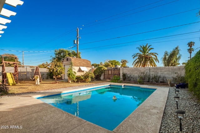 view of pool with a playground, a patio area, and a storage unit