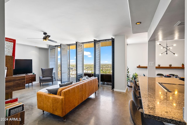 living room featuring ceiling fan with notable chandelier, a wall of windows, and concrete flooring