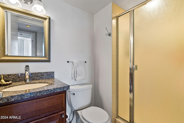 bathroom with toilet, a shower with door, and vanity