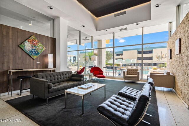 207 W Clarendon Ave Unit 20B, Phoenix, AZ 85013 - living room featuring visible vents, wooden walls, a towering ceiling, a raised ceiling, and expansive windows