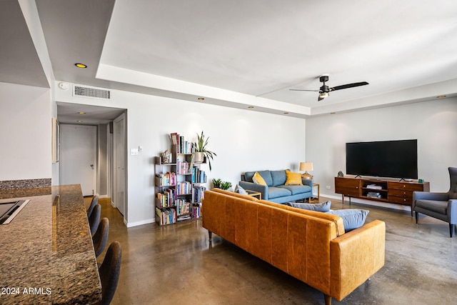 living room with a raised ceiling and ceiling fan