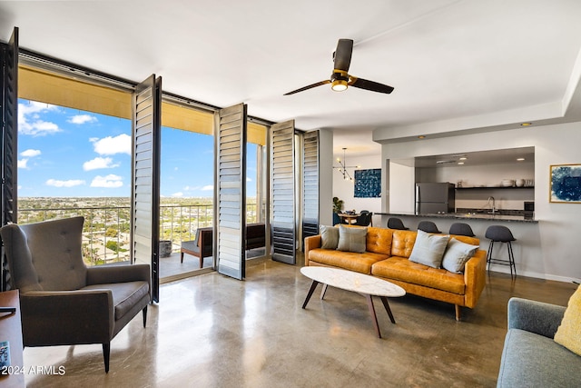 living room with floor to ceiling windows, ceiling fan, and concrete floors