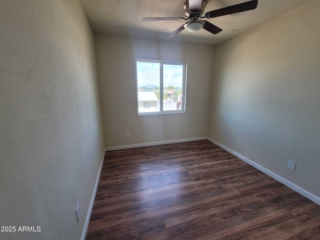 empty room with a ceiling fan, dark wood-style flooring, and baseboards