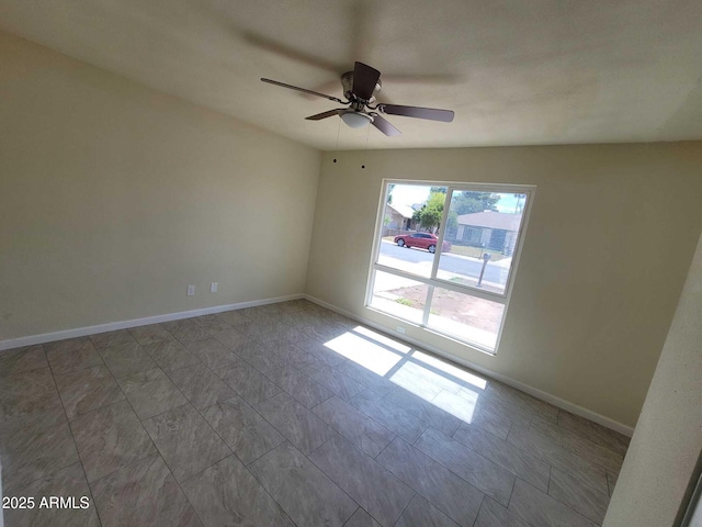 unfurnished room featuring ceiling fan and baseboards