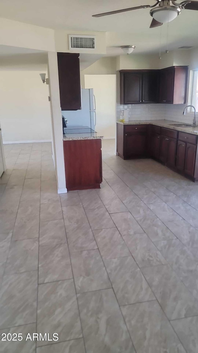 kitchen with decorative backsplash, visible vents, light countertops, and a sink