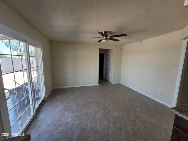 spare room featuring a ceiling fan, baseboards, and a textured ceiling