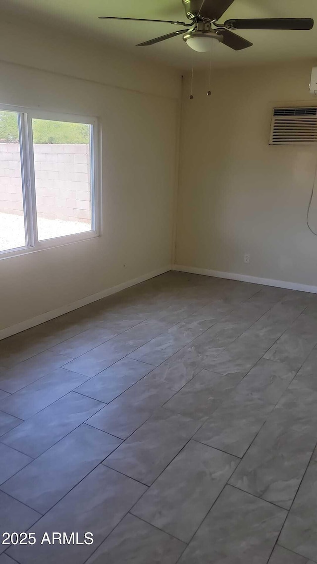 unfurnished room with ceiling fan, baseboards, and a wall mounted air conditioner