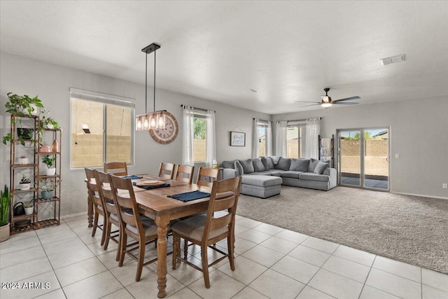 carpeted dining area featuring ceiling fan with notable chandelier and a wealth of natural light