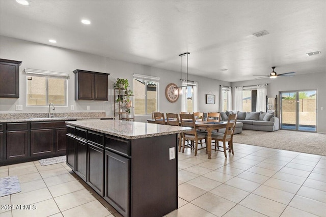 kitchen with sink, a kitchen island, light carpet, decorative light fixtures, and ceiling fan