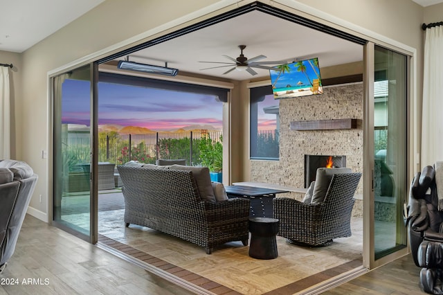 interior space featuring wood-type flooring, a stone fireplace, and ceiling fan