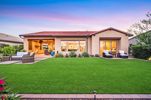 back house at dusk with a lawn, a patio area, and an outdoor hangout area