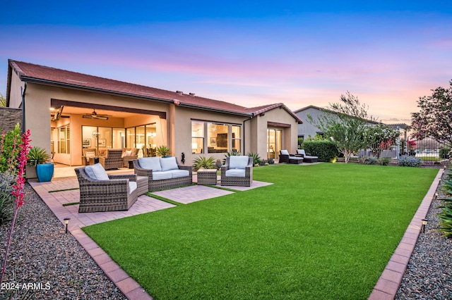 back house at dusk featuring a lawn, a patio area, and an outdoor living space