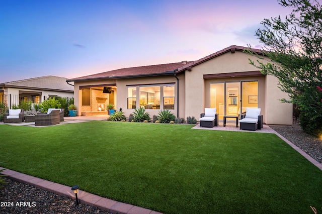 back house at dusk with a lawn, a patio area, and an outdoor hangout area