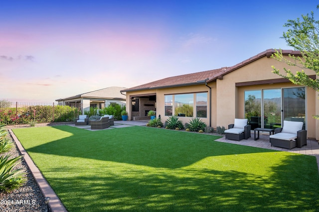 back house at dusk with a lawn, a patio area, and an outdoor hangout area