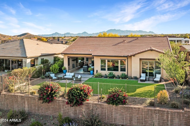 rear view of house with outdoor lounge area, a mountain view, a patio area, and a lawn