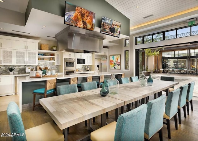 dining room featuring light hardwood / wood-style floors, wood ceiling, and high vaulted ceiling