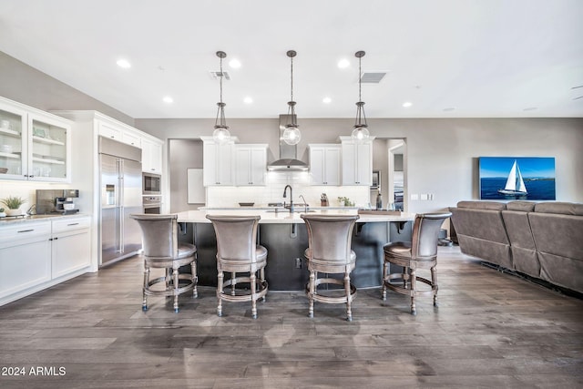 kitchen featuring pendant lighting, a breakfast bar, built in appliances, and white cabinets