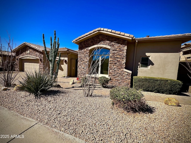 view of front of house with an attached garage, stone siding, and stucco siding