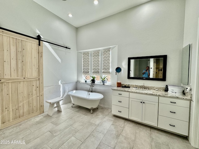 full bath featuring recessed lighting, a freestanding bath, and vanity