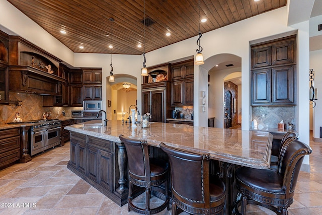 kitchen with wood ceiling, dark brown cabinetry, appliances with stainless steel finishes, and a spacious island