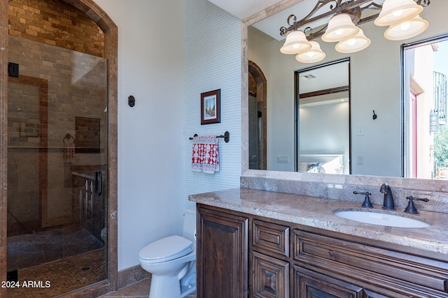 bathroom featuring a shower with door, vanity, and toilet