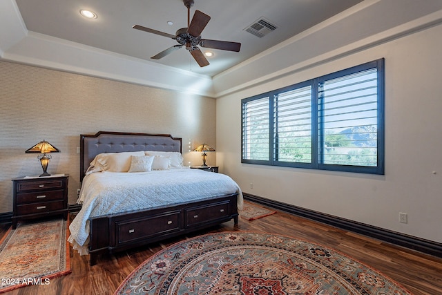 bedroom with ceiling fan, dark hardwood / wood-style floors, and a raised ceiling