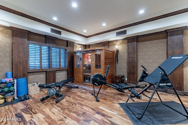 exercise area with crown molding and light wood-type flooring