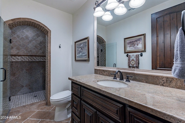 bathroom featuring vanity, a shower with door, and toilet