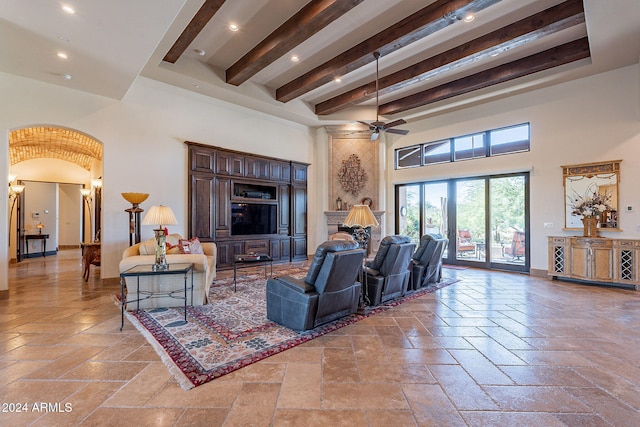 living room featuring a high ceiling, ceiling fan, and beam ceiling