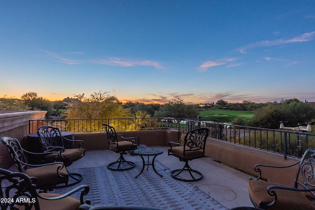 patio terrace at dusk featuring a balcony