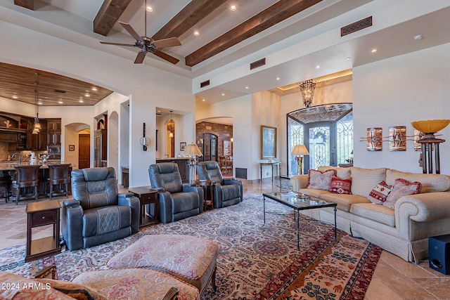 living room featuring beamed ceiling, a towering ceiling, and ceiling fan