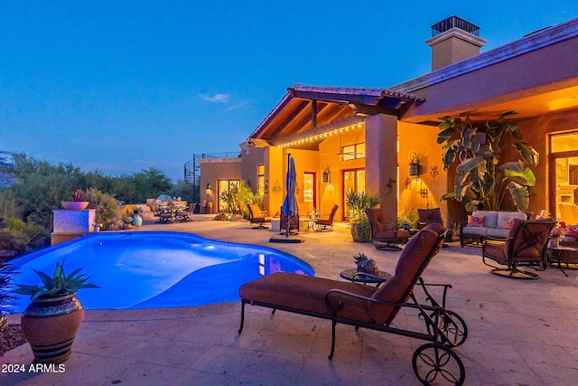 pool at dusk with an outdoor hangout area and a patio area