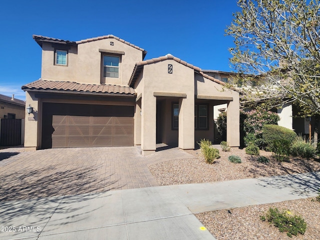 mediterranean / spanish-style house with a tile roof, decorative driveway, a garage, and stucco siding