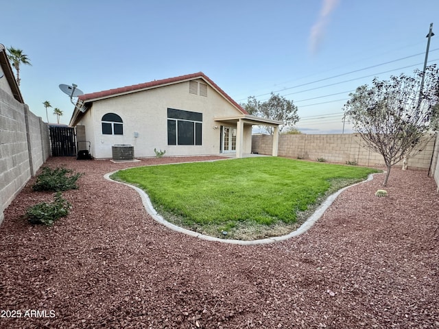 rear view of house featuring central AC unit, a fenced backyard, and stucco siding