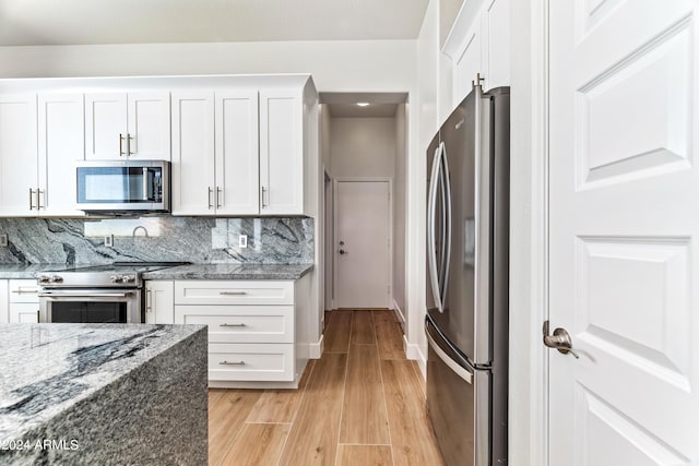 kitchen with stainless steel appliances, light wood finished floors, backsplash, and white cabinetry