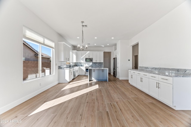 kitchen featuring tasteful backsplash, stainless steel appliances, light wood-type flooring, white cabinetry, and a sink