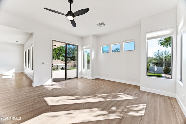 spare room with a ceiling fan, visible vents, baseboards, and wood finished floors