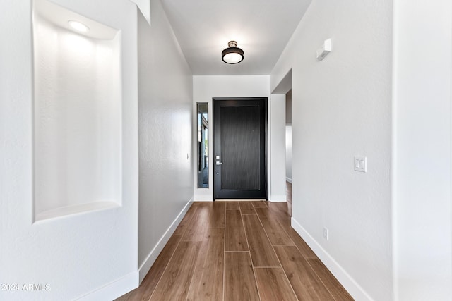 doorway featuring baseboards and wood finished floors