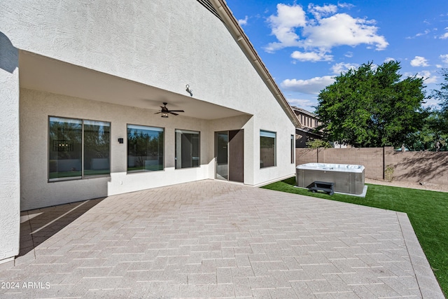 view of patio featuring a ceiling fan, fence, and a hot tub