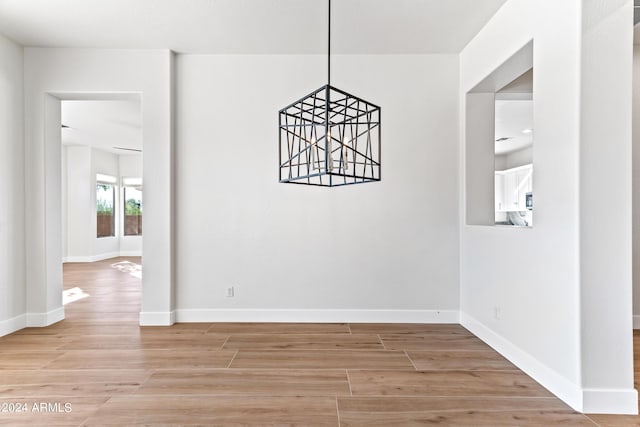 unfurnished dining area featuring baseboards and light wood-style floors