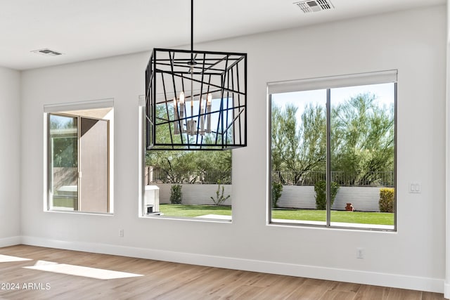 unfurnished dining area with visible vents, baseboards, and wood finished floors