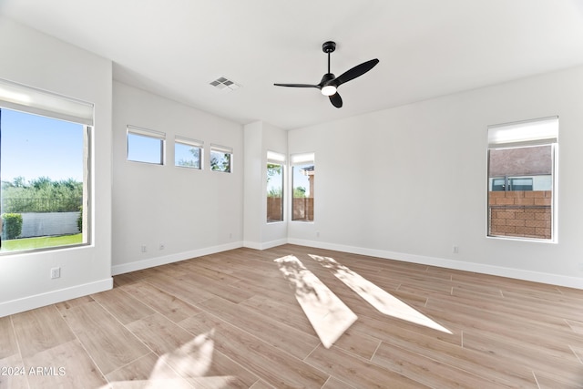 spare room with light wood-type flooring, baseboards, visible vents, and ceiling fan