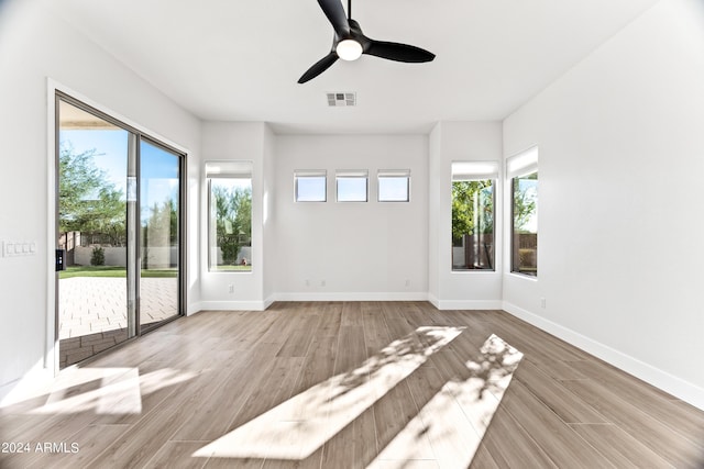 unfurnished room featuring baseboards, plenty of natural light, visible vents, and wood finished floors