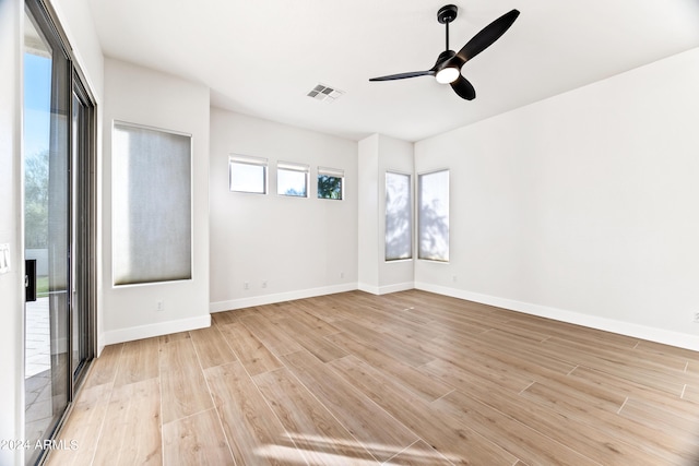 empty room with a ceiling fan, light wood-type flooring, visible vents, and baseboards