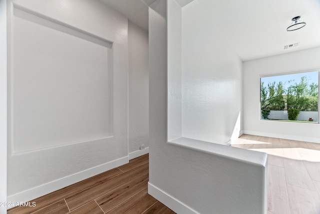 hall featuring baseboards, visible vents, and wood finished floors