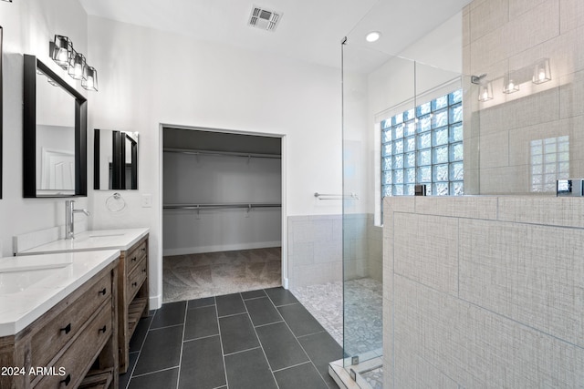 bathroom featuring double vanity, visible vents, a sink, walk in shower, and tile patterned floors