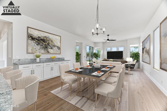 dining space featuring baseboards, plenty of natural light, a notable chandelier, and light wood finished floors