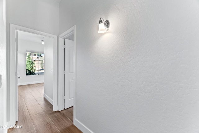 hall with baseboards and wood finished floors