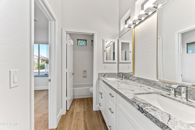 bathroom featuring double vanity, a sink, toilet, and wood finished floors