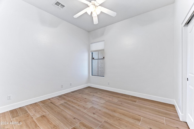 empty room featuring a ceiling fan, light wood-style flooring, visible vents, and baseboards